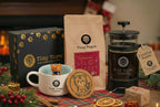 Tiny Tiger Coffee products including a mug, coffee beans, and a press on a festive table with decorations.